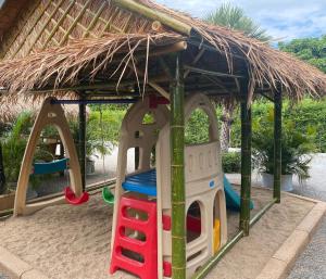 ein Spielplatz mit Strohdach und Spielgeräten in der Unterkunft SB Holiday Resort Chiang Mai in Chiang Mai