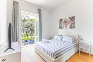 Elena House Apartments في فياريجيو: غرفة نوم بيضاء مع سرير وباب زجاجي منزلق