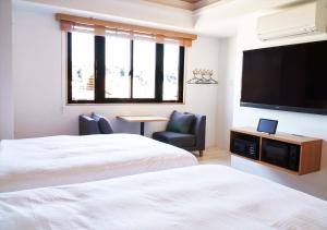 a hotel room with two beds and a flat screen tv at fav Hida Takayama in Takayama +39 photos