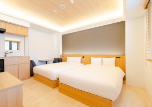 two beds in a hotel room with a kitchen at fav Hida Takayama in Takayama