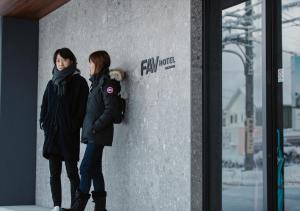 高山市にあるFAV HOTEL HIDATAKAYAMA Westの二人の女性が壁の隣に立っている