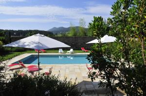 two umbrellas and chairs next to a swimming pool at Ai Lecci in Centro in Sarteano