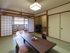 a living room with a table and a dining room at Hotel Tenzankaku Kaiyutei in Shirahama