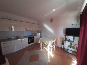 a kitchen with white cabinets and a table with chairs at Apartments Donadic I, Caska in Novalja
