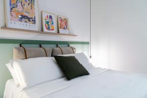 Una cama blanca con una almohada verde encima. en Stylish apartment with an arty touch Fast WiFi, en Trieste