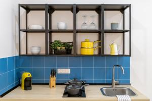 Una cocina con paredes de azulejos azules y estantes con platos. en Stylish apartment with an arty touch Fast WiFi, en Trieste 11 fotos más