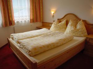 a bedroom with a large bed with a wooden headboard at Landhaus Marten in Saalbach-Hinterglemm