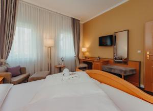 ein Hotelzimmer mit einem großen Bett und einem Spiegel in der Unterkunft Hotel Jungclaus in Wentorf bei Hamburg