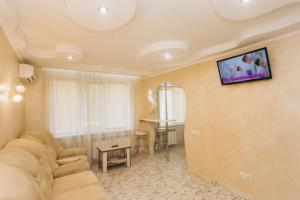 ein Wohnzimmer mit einem Sofa und einem TV an der Wand in der Unterkunft VIP Харьковская in Sumy