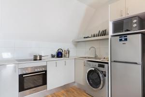 a kitchen with white cabinets and a washer and dryer at Urban Oasis Aparthotel in Cape Town