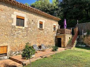 una casa de piedra con dos sillas delante en Can Gich Espacio Rural en Celrá