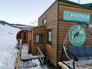 una cabaña de madera con un cartel en la nieve en Tinyhouse Postalm, en Abtenau