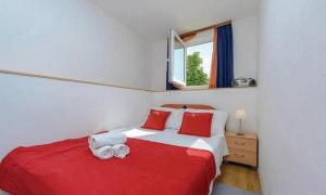 a bedroom with a red and white bed and a window at Apartments Raguz in Cavtat