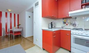 ツァヴタットにあるApartments Raguzの赤いキャビネットとテーブル付きのキッチンが備わります。