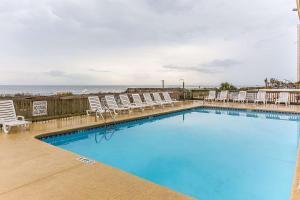 a large swimming pool with chairs and the ocean at Ocean Star Hotel in Myrtle Beach