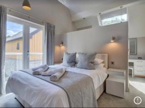 a bedroom with a large white bed with a window at Priory House; sleeps 6-20 in Goodleigh
