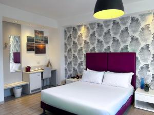 Schlafzimmer mit einem großen Bett mit einem lila Kopfteil in der Unterkunft Hotel Rossovino Como in Como