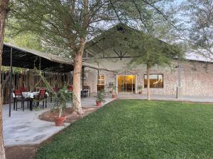 a house with a patio and a grass yard at Little Sossus Lodge in Sesriem