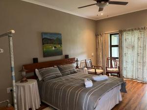 a bedroom with a large bed and a ceiling fan at Berlouri Guest House in Hekpoort