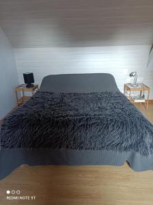 um quarto com uma cama com um edredão preto em petite maison de ville toute équipée em Château-Renard
