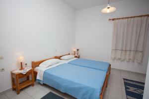 a bedroom with a bed with a blue blanket and a table at Anestoula Rooms in Skala