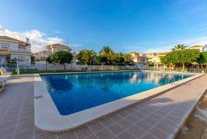 una piscina en una villa con palmeras y casas en HE DORIS, en Playa Flamenca