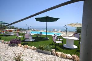 un patio con tavoli, sedie e piscina di Punto di vista a Roseto degli Abruzzi