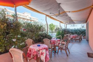 patio ze stołami i krzesłami z różowym blatem w obiekcie Hotel Joli w Cesenatico