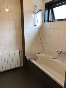 a bathroom with a bath tub with a shower at Pension Brinkvis in De Koog +8 photos