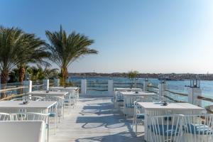 een rij tafels en stoelen op een promenade naast het water bij Sunrise Tucana Resort Grand Select- in Hurghada