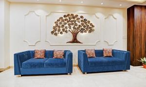 ボーパールにあるHotel Yuvraj Palaceの壁に木が描かれた客室内の青いソファ2台
