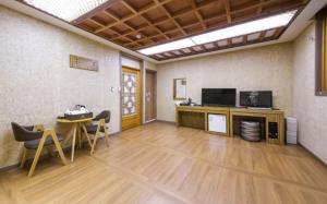a room with a table and a television and a table and chairs at Jeonju Hanok Hotel Kung in Jeonju