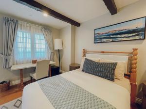 a bedroom with a bed and a desk and a window at Zane Grey Pueblo Hotel in Avalon