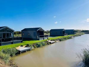 a row of houses on the side of a river at Chapel Fields Holiday Park in Chapel Saint Leonards