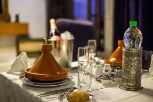 a table with a white table cloth with a bottle on it at Riad Braya in Fès