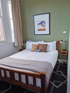 a bedroom with a large bed with white sheets and pillows at The Empire Hotel in Deloraine