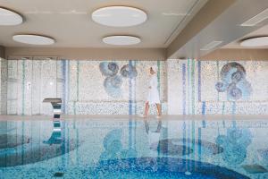 a woman walking in front of a swimming pool at Hotel AMI Budva Petrovac in Petrovac na Moru