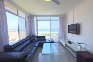 een woonkamer met een zwarte leren bank en een televisie bij 41 Licorna Beach in Durban