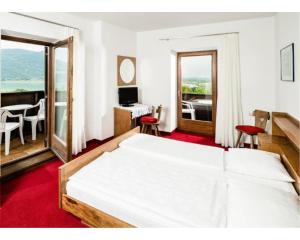 - une chambre avec un grand lit blanc et un bureau dans l'établissement Pension Hasslhof, à Caldaro