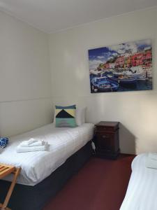 a bedroom with a bed, desk and a painting on the wall at The Empire Hotel in Deloraine