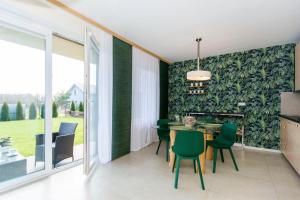 a dining room with a table and green chairs at Apartament Zen in Sobieszewo