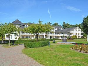 ein großes weißes Gebäude mit einem Backsteinweg davor in der Unterkunft Dünenpark Binz - WG 73 "Strandläufer" mit Terrasse in Binz