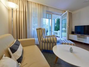 ein Wohnzimmer mit einer Couch, einem Tisch und einem Fernseher in der Unterkunft Dünenpark Binz - WG 73 "Strandläufer" mit Terrasse in Binz