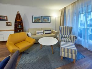 ein Wohnzimmer mit einer Couch und einem Tisch und Stühlen in der Unterkunft Dünenpark Binz - WG 73 "Strandläufer" mit Terrasse in Binz