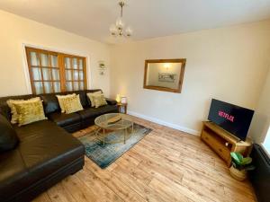 a living room with a black couch and a tv at Cherry Tree Lodge in Norwich