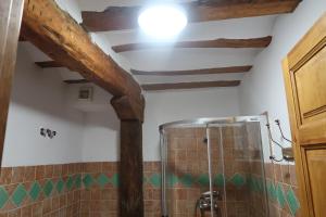 y baño con vigas de madera y cabina de ducha. en Casa Barría en Pradoluengo