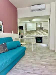 a living room with a blue couch and a kitchen at Charmrooms in Castellammare del Golfo