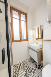 ein Bad mit einem Waschbecken und einem Spiegel in der Unterkunft L'avant-gardiste - Appart'Hotel Le Gatsby in Saint-Quentin
