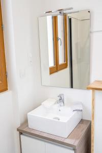 ein Badezimmer mit einem weißen Waschbecken und einem Spiegel in der Unterkunft L'avant-gardiste - Appart'Hotel Le Gatsby in Saint-Quentin