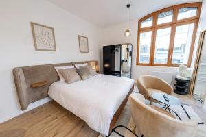 ein Schlafzimmer mit einem großen Bett und einem Stuhl in der Unterkunft L'avant-gardiste - Appart'Hotel Le Gatsby in Saint-Quentin
